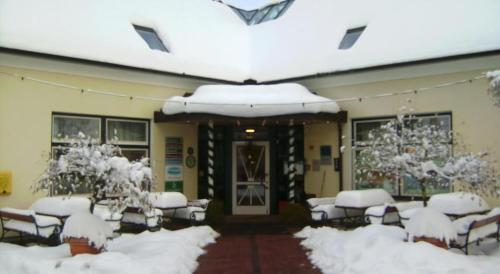 a building covered in snow with tables and chairs at Thermen Apartment in Bad Waltersdorf