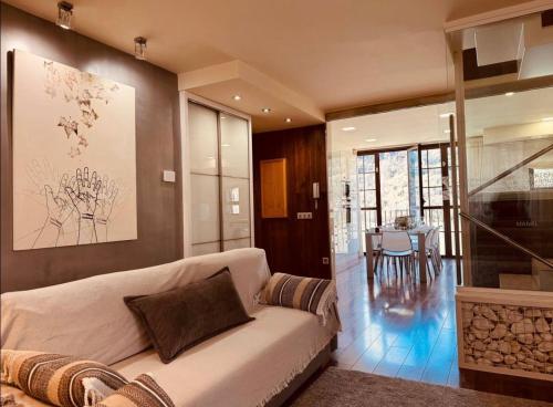 a living room with a white couch and a table at CASA PIXURRI en Lanuza compuesta de 5 apartamentos turísticos en casona pirenaica, a 10 minutos de las ESTACIONES de ESQUÍ de FORMIGAL-PANTICOSA in Lanuza