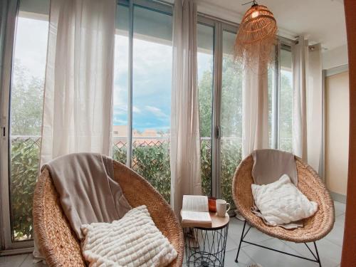 two wicker chairs in front of a large window at Appartement Coup de Coeur avec Parking et Piscine - 131 in Canet-en-Roussillon