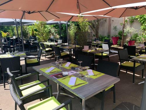 a restaurant with tables and chairs and umbrellas at Hôtel Restaurant Au Boeuf in Blaesheim