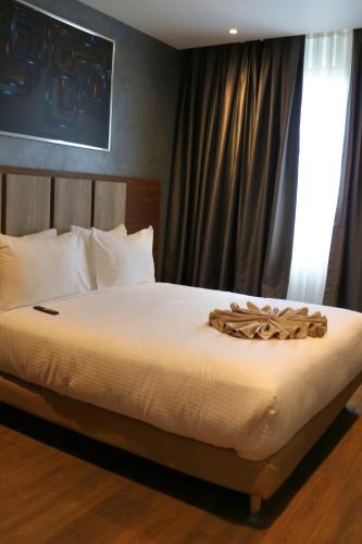 a bedroom with a bed with white sheets and a window at El Aziz Inn in Cheraga