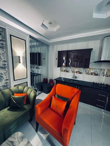 a living room with an orange chair and a couch at Apartment in Bahria Town Grand heights 8 Lahore in Lahore