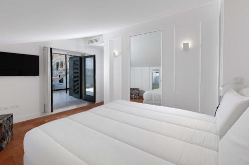 a white bedroom with a large white bed and a tv at AMORE RENTALS - The Square Penthouse in Sorrento