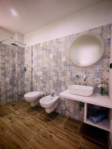 a bathroom with a sink and a toilet and a mirror at Mes'e Làmpadas in Castelsardo