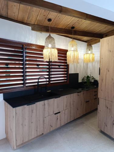 a kitchen with two chandeliers and a counter with a sink at La Kaz Banian in Saint-Pierre
