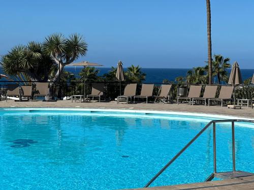a large blue swimming pool with chairs and umbrellas at Aquamarina Gran Canaria in Los Caideros