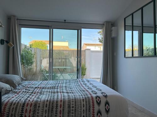 une chambre avec un lit et une grande fenêtre dans l'établissement Maison & studio, jardin, tout confort, à Aigues-Mortes