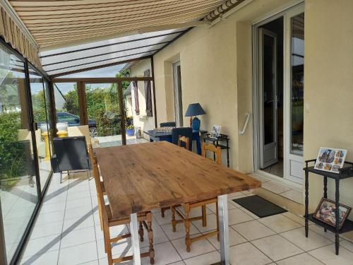 une table et des chaises en bois sur une terrasse dans l'établissement Maison spacieuse et lumineuse à seulement 1 minute de la mer, à Rosnoën