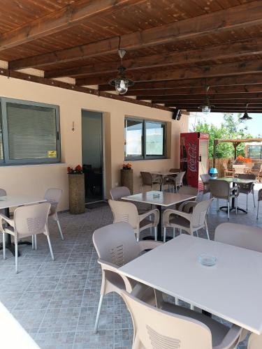 a restaurant with white tables and chairs and windows at GOLDEN BEACH in Souvala