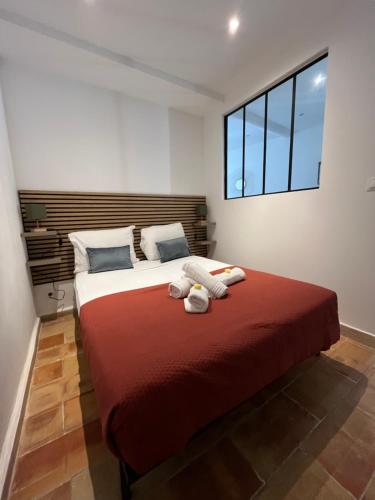 une chambre avec un grand lit avec une couverture rouge dans l'établissement Chez Balthazar n2 Arles centre, à Arles