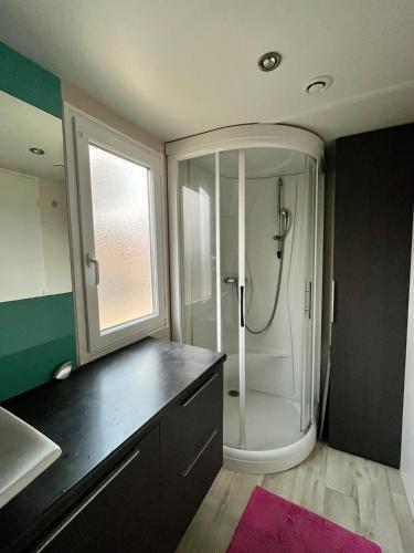 La salle de bains est pourvue d'une douche et d'un comptoir noir. dans l'établissement Mobil home climatisé Louisiana 4 pers, à Sémussac