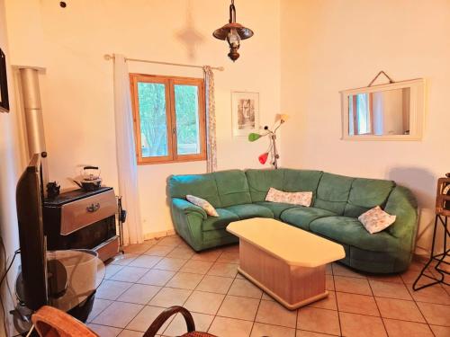 un soggiorno con un divano verde e un tavolo di Le Bastidon de Dudule a Montagnac