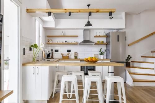 a kitchen with white cabinets and bar stools at koukou house skopelos in Skopelos Town