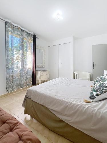 une chambre blanche avec un grand lit et un bureau dans l'établissement Le clos des vignes, à Puyméras