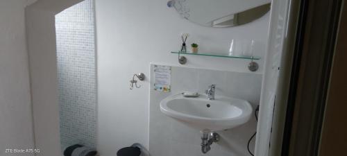 a white bathroom with a sink and a mirror at La Castagna Matta in Albareto