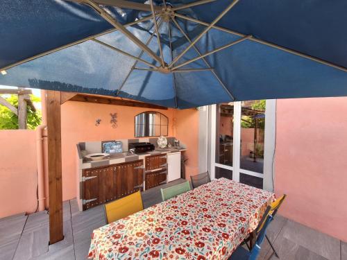 une terrasse avec une table et un parasol bleu dans l'établissement La maison rose, à Avignon