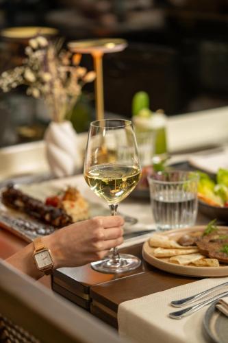 a person holding a glass of white wine on a table at Querencia Hotel in Istanbul