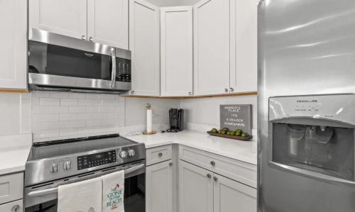 a kitchen with white cabinets and a stainless steel refrigerator at Sol Shine Gulf-View Retreat Steps from the Sand in Mexico Beach