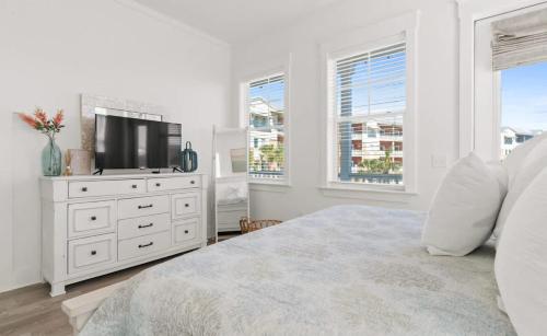 a white bedroom with a television and a white dresser at Sol Shine Gulf-View Retreat Steps from the Sand in Mexico Beach