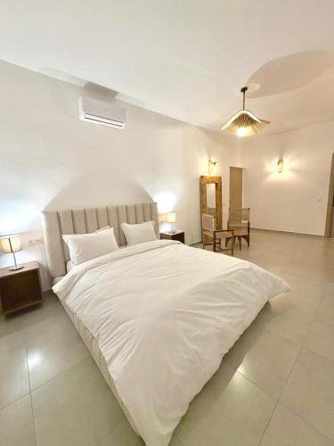 a bedroom with a large white bed and a table at Villa Elysia in Ech Chaïbat
