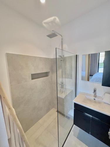 a bathroom with a glass shower and a sink at Villa Elysia in Ech Chaïbat