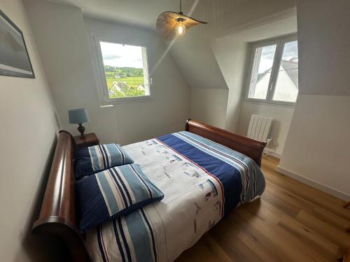 a bedroom with a bed and two windows at Maison spacieuse et lumineuse à seulement 1 minute de la mer in Rosnoën