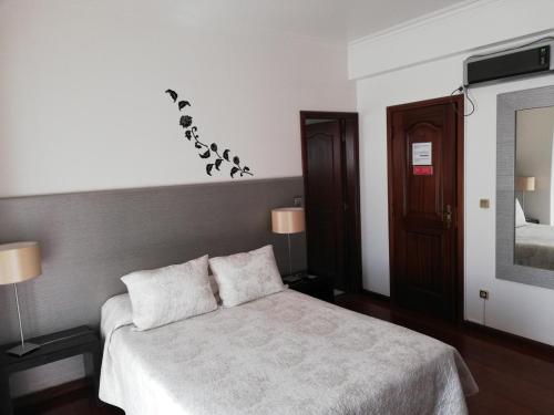 a bedroom with a bed and two lamps and a mirror at Residência Maciel in Peniche