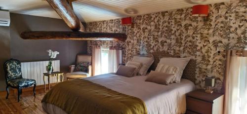 - une chambre avec un grand lit dans une pièce avec du papier peint dans l'établissement Demeure de Charme Les Lanternes, à Lignan-sur-Orb