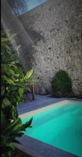 - une piscine avec un banc à côté d'un mur en pierre dans l'établissement Demeure de Charme Les Lanternes, à Lignan-sur-Orb