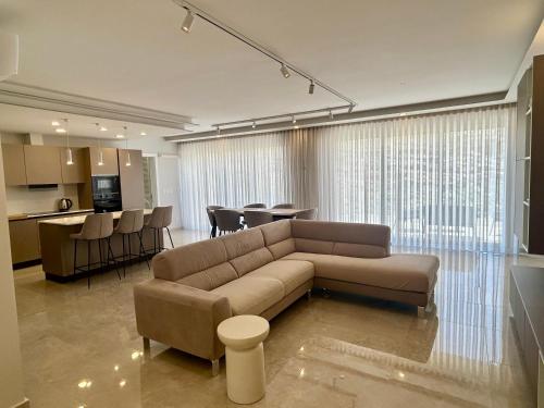 a living room with a brown couch and a kitchen at Seaview Penthouse Xlendi in Xlendi