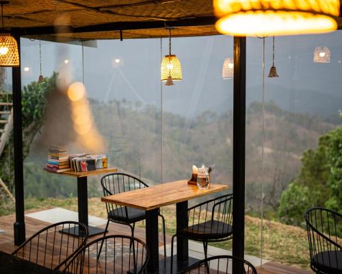 a table and chairs in front of a large window at Himadvaya- The Himalayan Prism in Almora
