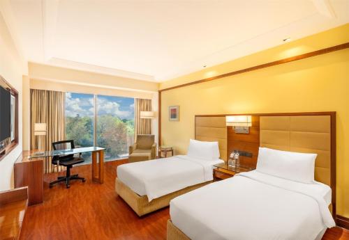 a hotel room with two beds and a desk at Park Inn Gurgaon in Gurgaon