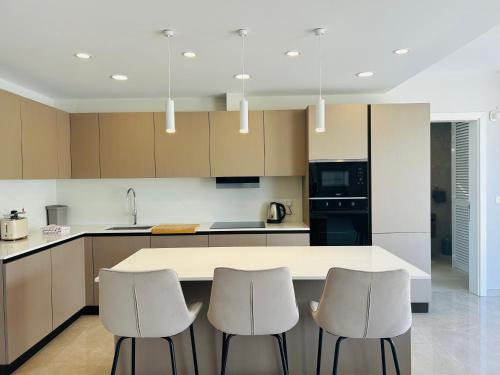 a kitchen with a white counter and two stools at Seaview Penthouse Xlendi in Xlendi