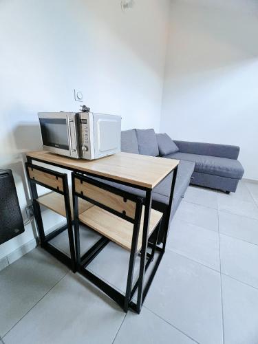 une table avec un micro-ondes et un canapé dans un salon dans l'établissement Sous les toits du centre-ville, à Narbonne