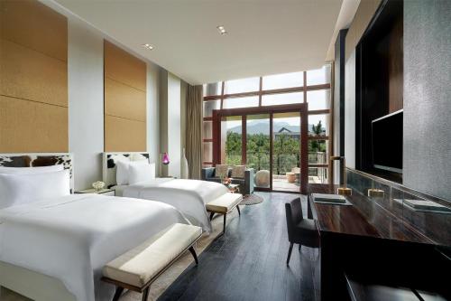a hotel room with four beds and a television at Yanqi Hotel, Managed by Kempinski in Huairou