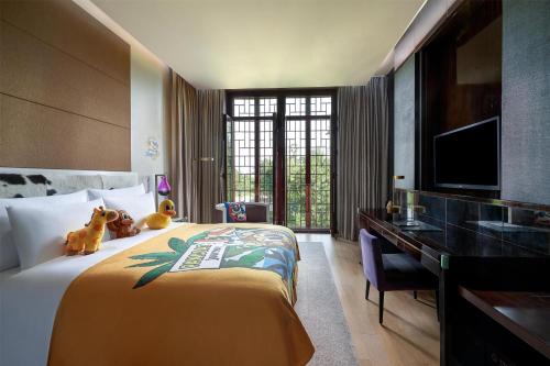 a hotel room with a bed with a desk and a television at Yanqi Hotel, Managed by Kempinski in Huairou