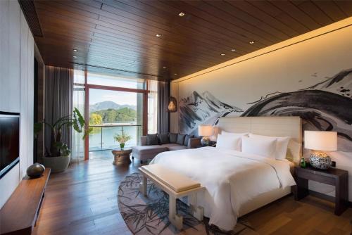 a bedroom with a large bed and a living room at Yanqi Hotel, Managed by Kempinski in Huairou