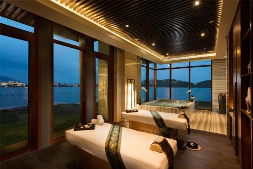a room with three beds and a bathtub and windows at Yanqi Hotel, Managed by Kempinski in Huairou