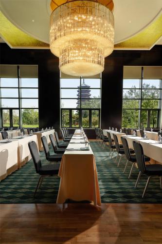 a dining room with tables and chairs and a chandelier at Yanqi Hotel, Managed by Kempinski in Huairou