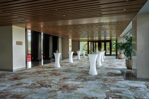 a hallway with white tables and potted plants at Yanqi Hotel, Managed by Kempinski in Huairou