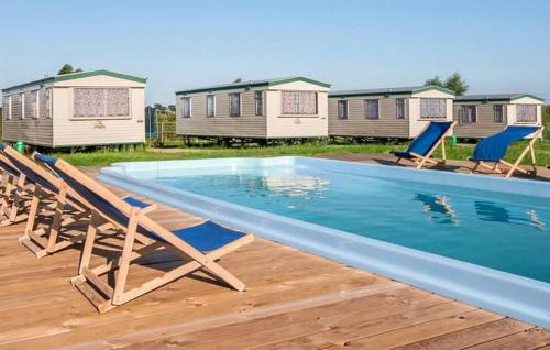 a swimming pool with chairs and a row of houses at Beautiful Home In Sarbinowo in Sarbinowo