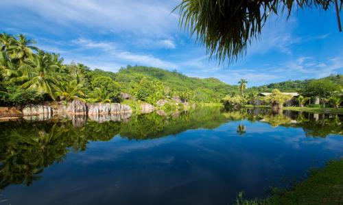 a view of a river with palm trees and a mountain at Kempinski Seychelles Resort in Baie Lazare Mahé