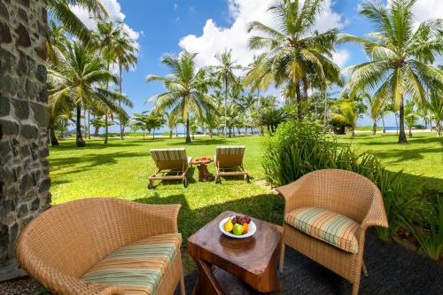 a patio with two chairs and a table with a bowl of fruit at Kempinski Seychelles Resort in Baie Lazare Mahé