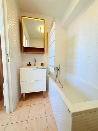 une salle de bain avec un lavabo, une baignoire et un miroir dans l'établissement Le Balcon de Saint-Clair, Joli T2 Centre, Climatisé, Parking privé, à Sète