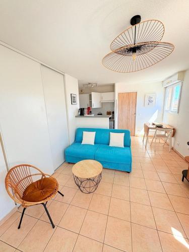un salon avec un canapé bleu et une table dans l'établissement Le Balcon de Saint-Clair, Joli T2 Centre, Climatisé, Parking privé, à Sète