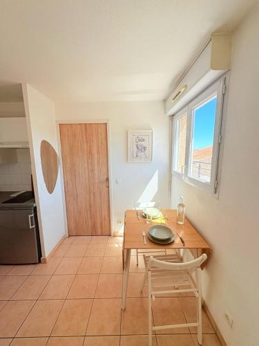 une salle à manger avec une table et des chaises et une fenêtre dans l'établissement Le Balcon de Saint-Clair, Joli T2 Centre, Climatisé, Parking privé, à Sète