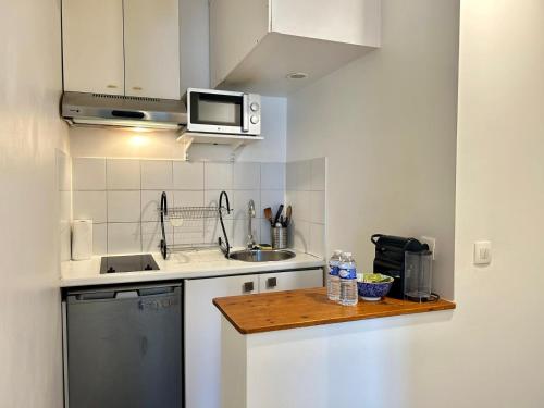 une petite cuisine avec un évier et un micro-ondes dans l'établissement Le Jaures - Centre ville Metro 3, à Levallois-Perret
