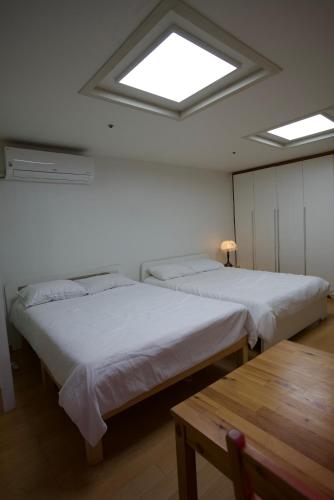 two beds in a room with a skylight at Hongdae Sky apartment in Seoul