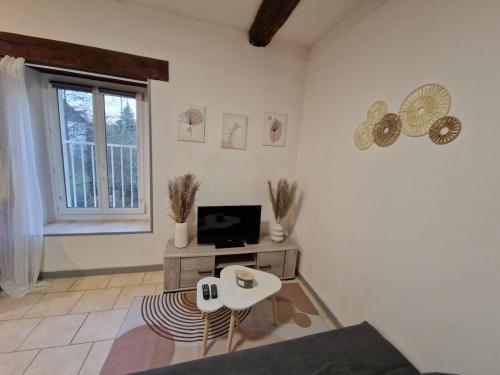 un salon avec une télévision et une table dans l'établissement Appartement De Charme, à Bourges