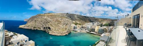 a view of a city with a mountain in the water at Seaview Penthouse Xlendi in Xlendi
